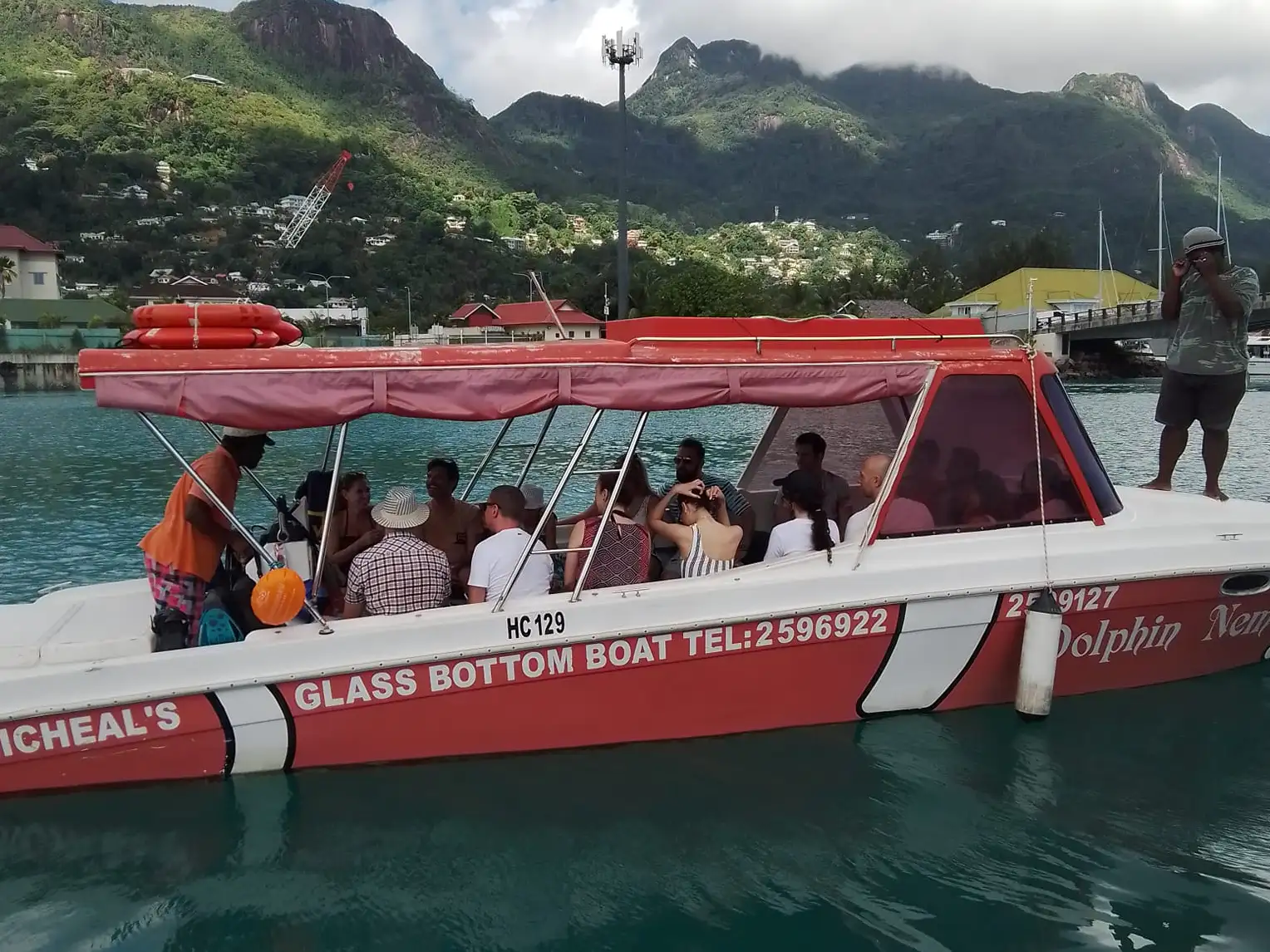 Guests and crew aboard Dolphin Nemo with the mountains of Mahé behind them